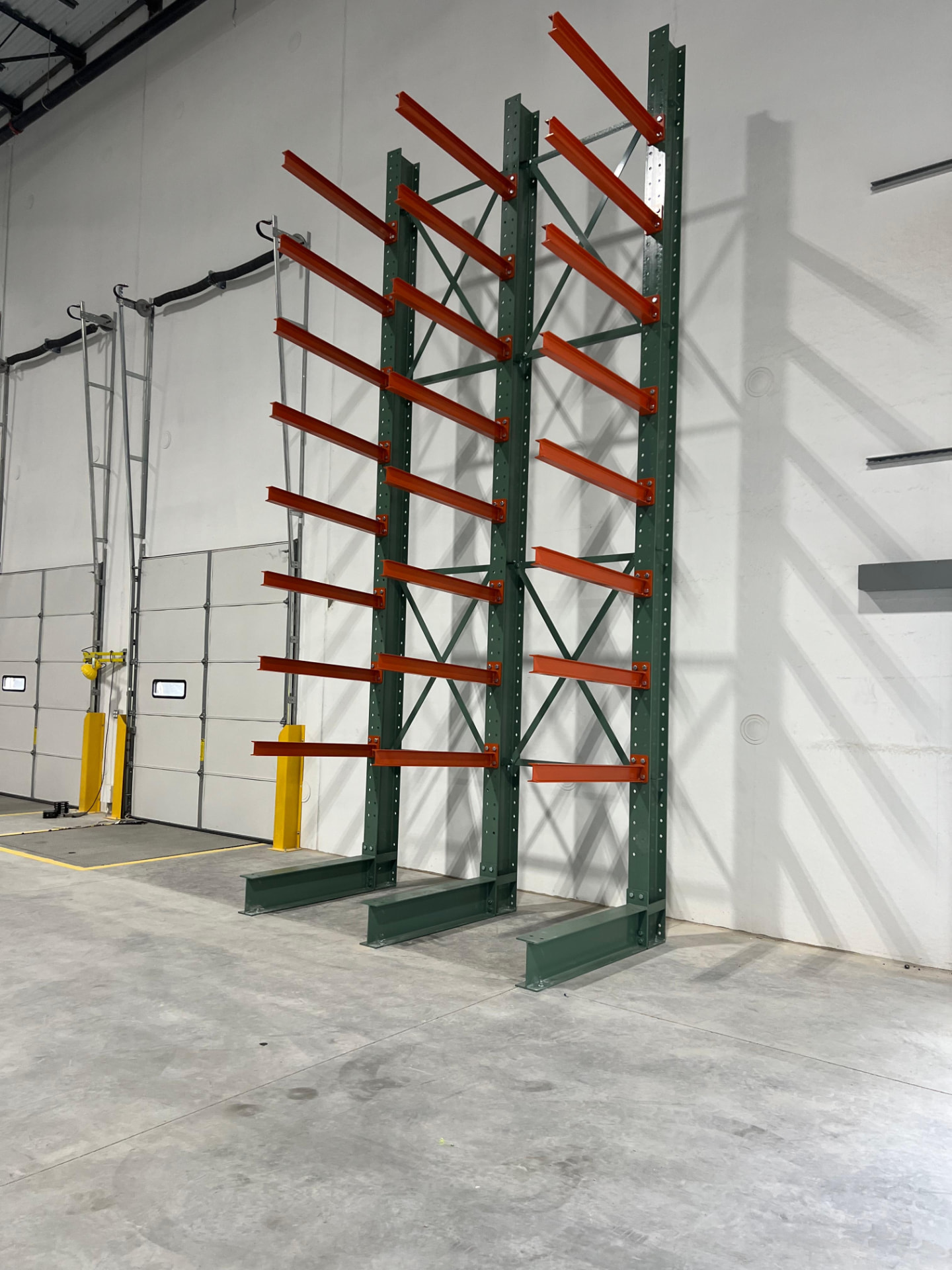 Cantilever rack with orange arms installed against a warehouse wall